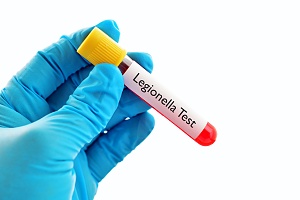 legionella in a test tube held by a employee wearing blue gloves