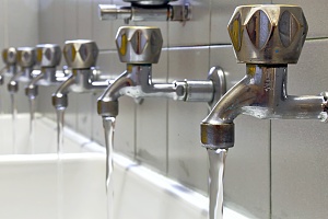 sinks in an educational facility with turned on with legionella compliant water coming out of the faucets