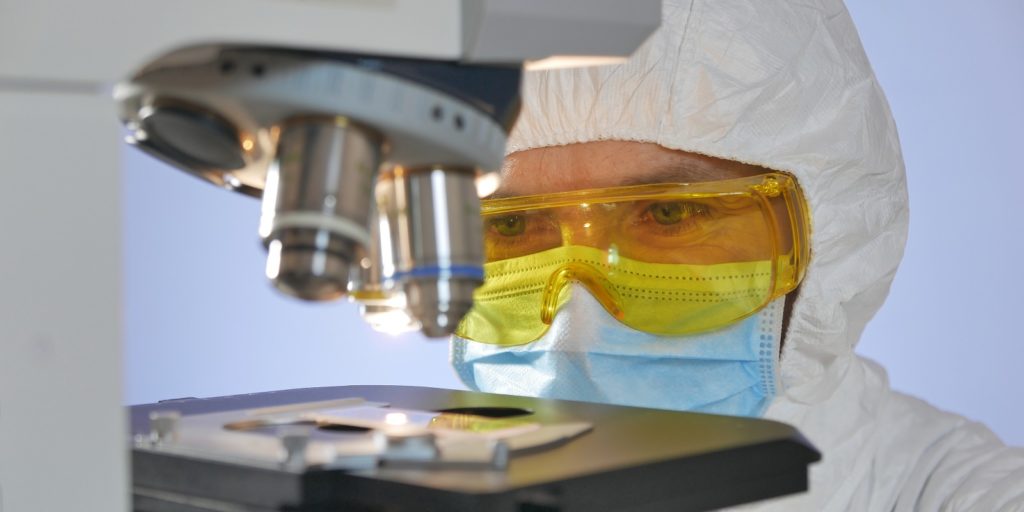 A lab technician conducting test for Legionella in water sample under microscope