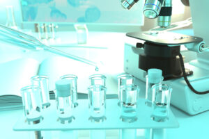test tubes containing samples that are being tested for legionella are next to a microscope