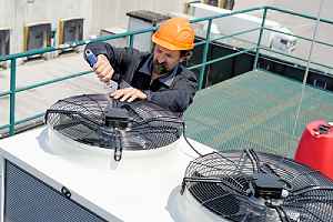 A worker conducting routine work at a rooftop cooling tower facility