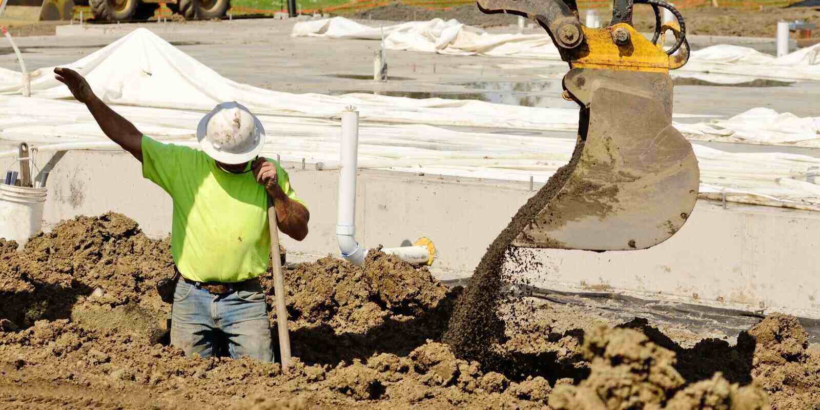 contractor using a small track hoe excavator to dig a water line trench for water treatment construction