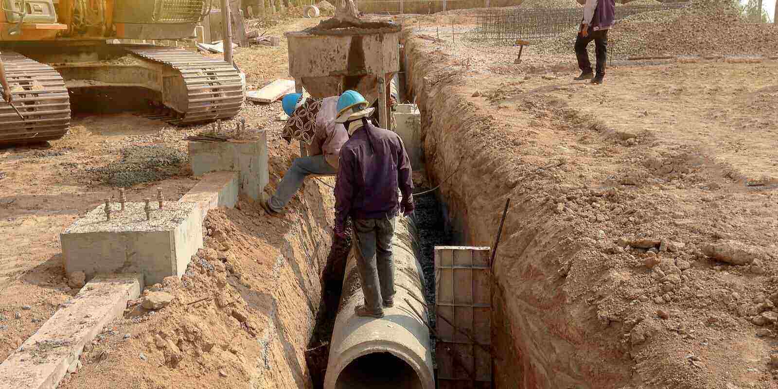 workers are installing concrete drains on the side of the road for water pipeline construction