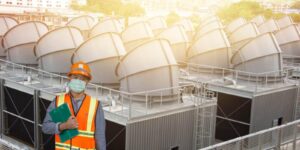 worker in protective helmet on cooling tower background
