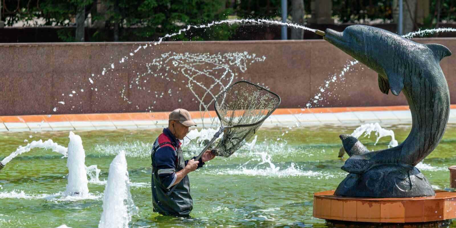 man cleans a fountain in a city park