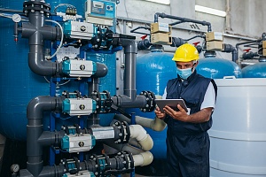 water treatment technician reviewing chemical water treatment equipment