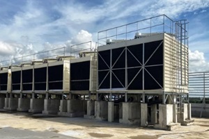 cooling tower is located in a large data center building installed on the roof on a bright blue sky. And there are white clouds