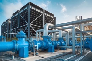 towering industrial cooling structures with blue valves, metal pipes under clear sky