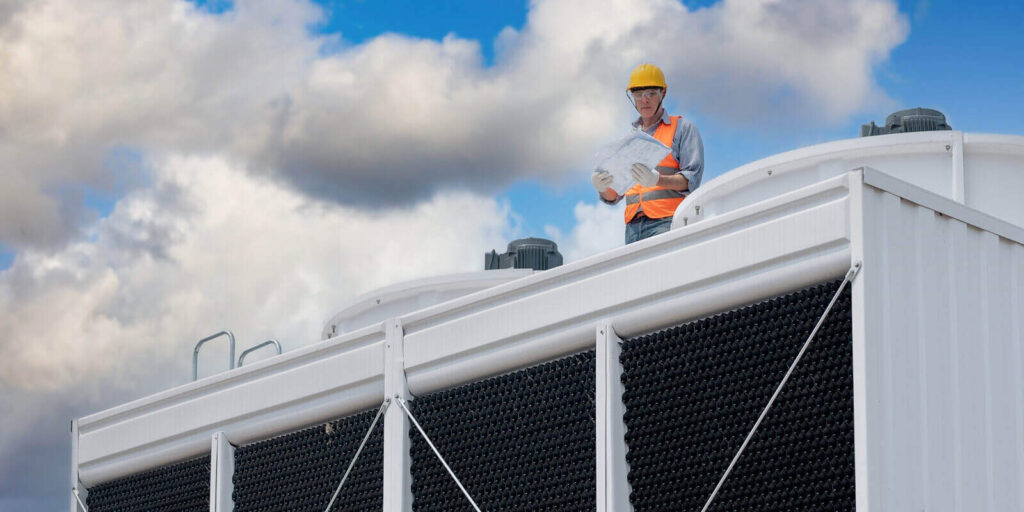 industry engineer under checking the industry cooling tower air conditioner is water cooling tower air chiller HVAC of large industrial building to control air system