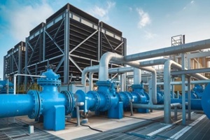 towering industrial cooling structures with blue valves, metal pipes under clear sky