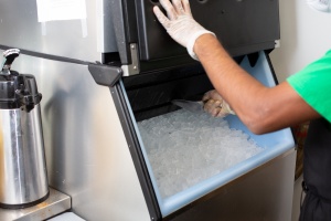 ice machine serviced by a kitchen staff member with a spatula. 